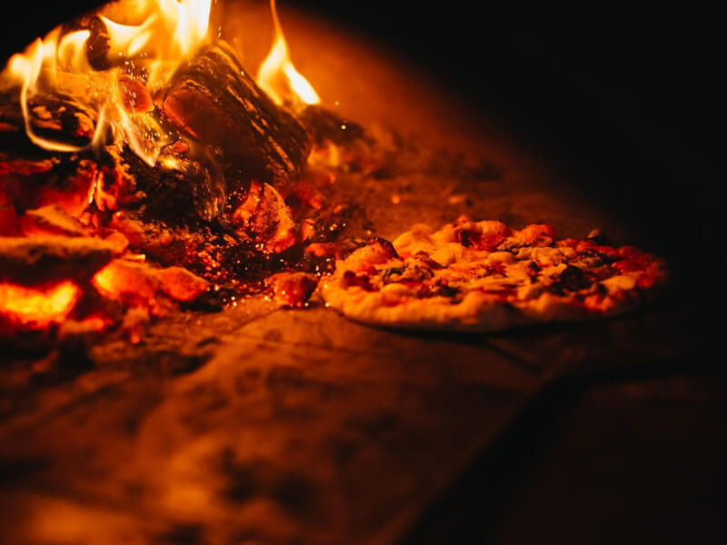 A Neapolitan pizza being cooked in a wood-fire oven